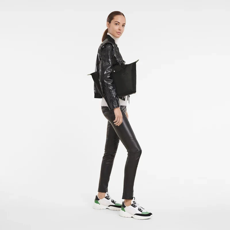 Longchamp Le Pliage Green M Tote bag in black, showing the foldable fabric bag with leather handles and logo detail.